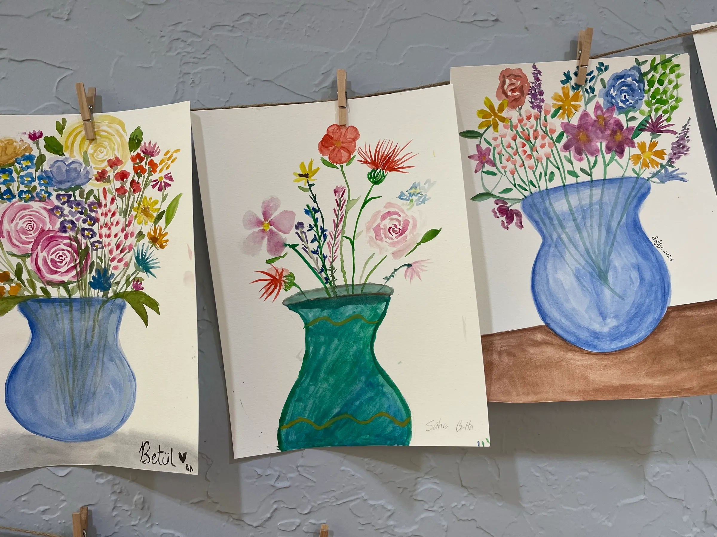 Student watercolor paintings of flowers in vases