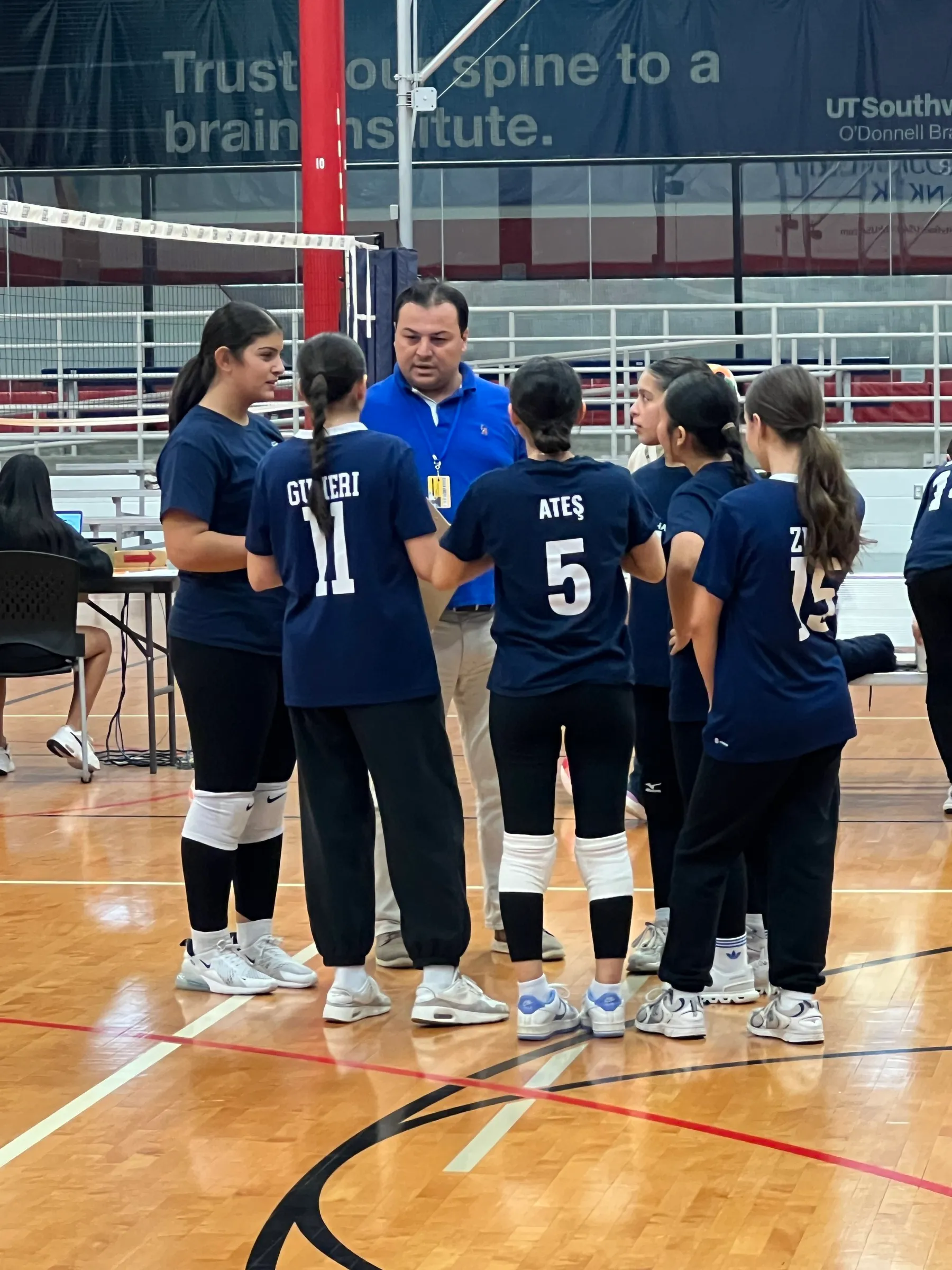 Volleyball team gathered around their coach at a tournament